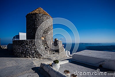 Typical stone building with thatched roof - granary - in resort in Santorini, Greece, with ocean and cliffs in the Stock Photo
