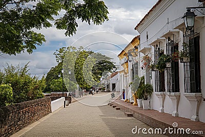 River promenade with historic white buildings, colorful pillars and trees trees of Santa Cruz de Mompox, Colombia, World Heritage Stock Photo