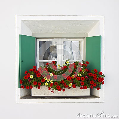 Typical swiss window with shutters in green and colorful flowers on the windowsill Stock Photo