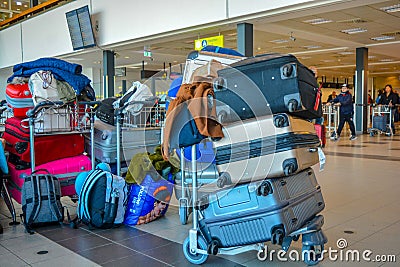 A typical travel scene: luggage cart full of baggages and bags in the middle of the airport terminal Editorial Stock Photo