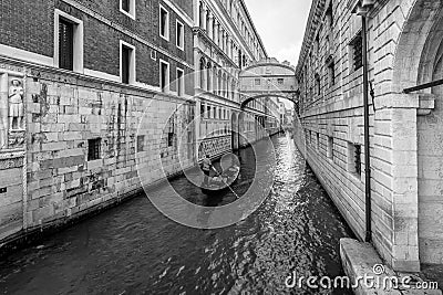 A typical Venetian gondola navigates the canal that passes under the famous Ponte dei Sospiri, Venice, Italy Editorial Stock Photo