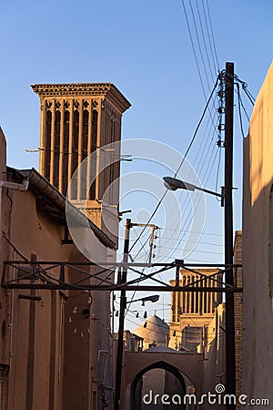 Typical Windtower made of clay taken in the streets of Yazd, iran, surrounded by power electrical lines. Stock Photo