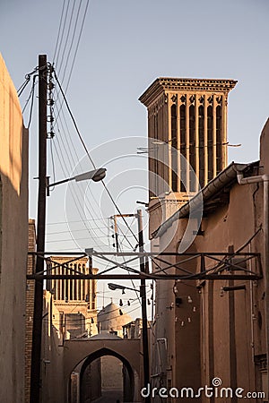 typical Windtower made of clay taken in the streets of Yazd, iran, surrounded by power electrical lines. Stock Photo