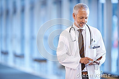 Typing, happy and a doctor with a tablet for healthcare, consulting and cardiology. Hospital, smile and a mature surgeon Stock Photo