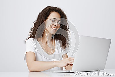 Typing message to answer on tricky question from friend. Pleased happy young woman working with laptop, smiling broadly Stock Photo