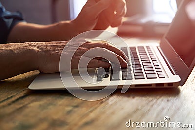 Typing on notebook computer, close up of hands of business man working on laptop. Side view, selective focus Stock Photo