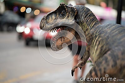 A Tyrannosaurus dinosaur, on a city background with lights from cars. Stock Photo