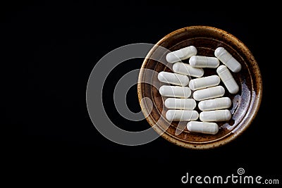 Tyrosine capsules one of the 20 standard amino acids. A dietary supplement used to improve attention and focus on black paper ba Stock Photo