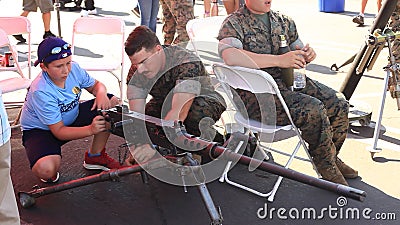 A U.S. Marine teaches a young boy how to use a machine gun Editorial Stock Photo