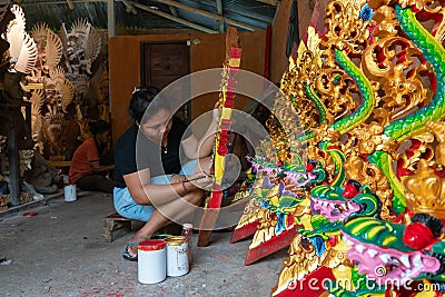 UBUD/INDONESIA-APRIL 27 2019: A female craftsman from Ubud is making dragon carving and coloring it using bright and attractive Editorial Stock Photo