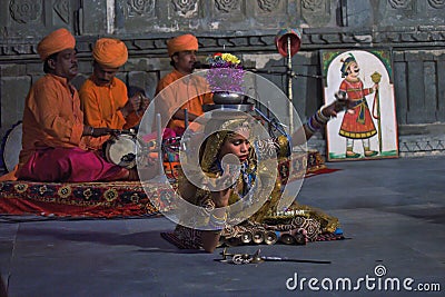 Udaipur, India - May 24, 2013: An Indian woman with earthen jar on fire balancing on their head while performing Rajasthani dance Editorial Stock Photo