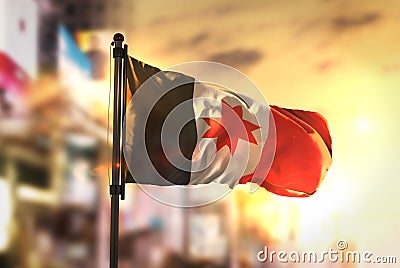 Udmurtia Flag Against City Blurred Background At Sunrise Backlight Stock Photo