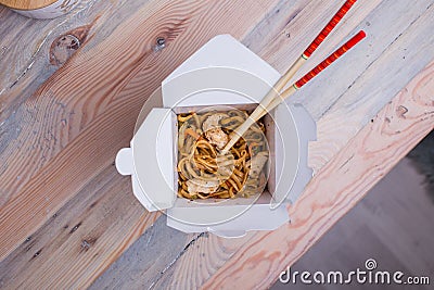 Udon stir fry noodles with chicken in a box on a wooden background Stock Photo