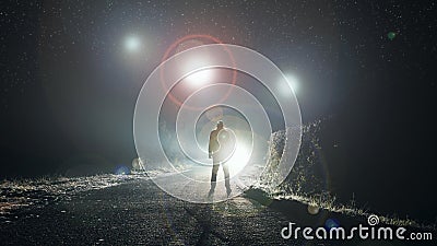 UFO concept. Glowing orbs, floating above a misty road at night. With a silhouetted figure looking at the lights Stock Photo