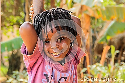 Ugandan African girl with dreadlocks smiles very cute while playing on the street of Kampala suburb Editorial Stock Photo