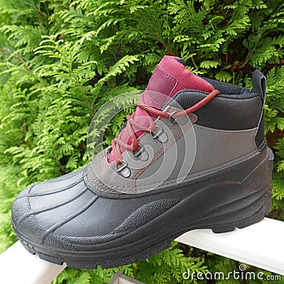 Rugged, waterproof outdoor boot for men, side view, in front of a green hedge Stock Photo