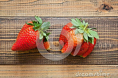 Ugly fruit. Misshapen produce concept. Organic deformed strawberries on wood background Stock Photo