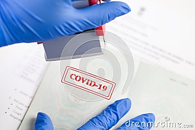 UK border security officer wearing blue protective gloves stamping COVID-19 onto document Stock Photo