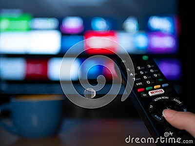 UK, Jan 2020: Netflix remote control with android apps on smart TV screen Editorial Stock Photo
