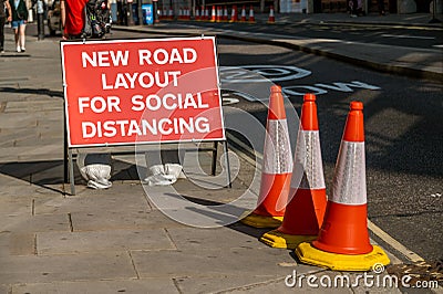 A UK road sign with orange traffic cones telling users that the layout has changed to allow for social distancing during Covid 19 Stock Photo