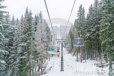 Ukraine, Bukovel - December 15, 2018. Lots of snowboarders and skiers lift to snow hill by elevator. Mountain ski spot in winter Editorial Stock Photo