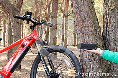 Ukraine Dnipro 05.04.2021 - a red electric bike is recharged in a forest in a park, new technologies Editorial Stock Photo