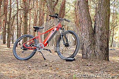 Ukraine Dnipro 05.04.2021 - a red electric bike is recharged in a forest in a park, new technologies Editorial Stock Photo