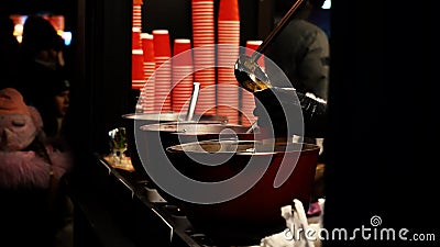 Ukraine. Kyiv. 12.2021: Pots of hot fragrant mulled wine at a street winter fair from which steam is brewed Editorial Stock Photo