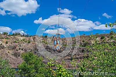 Zipline. The men in the equipment slides on a steel cable. Trolley Track Over the lake. Extreme and active rest. Editorial Stock Photo