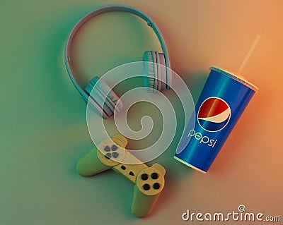 UKRAINE, ODESSA-JANUARY 10, 2019: Pepsi paper cup with straw, headphones, gamepad. Relax concept, gamer, top view, neon light. Editorial Stock Photo