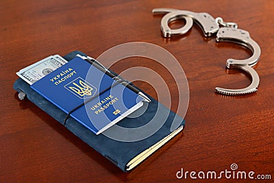 Ukrainian biometric passport and handcuffs on the table.Ukrainian biometric passport. Stock Photo