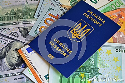 The Ukrainian biometric passport is on paper euro bills and dollars. Concept: increase of salaries, Ukrainians go abroad to work Stock Photo