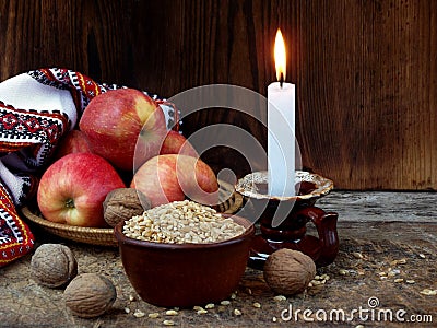 Ukrainian Christmas concept for greeting card. Composition of burning candle, apples, walnuts, wheat on wooden background. Copy sp Stock Photo