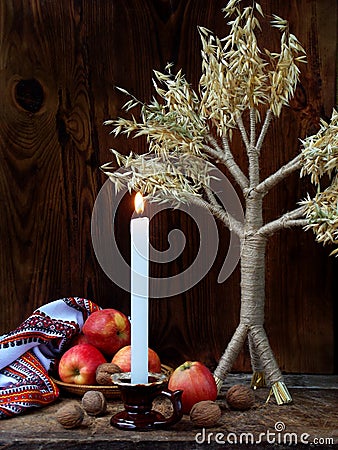 Ukrainian Christmas concept for greeting card. Composition of xmas symbol didukh, burning candle, apples, walnuts on wooden backgr Stock Photo