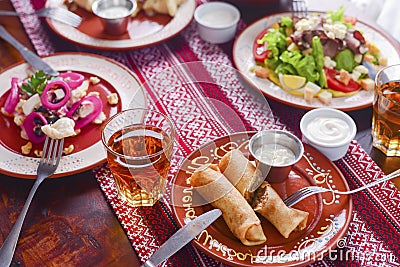 Ukrainian family in traditional closes has a dinner. Ukrainian culture. Family eating and clang glasses together. Stock Photo