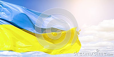 Ukrainian flag against a blue cloudy sky. Flag of Ukraine in sunlight and glare. Blue and yellow flag develops Stock Photo