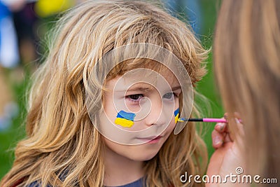 Ukrainian flag on child cheek. Human protest. Stock Photo