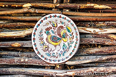 Ukrainian handmade earthenware utensil. Painted plate on wooden wall. Souvenirs From Ukraine in ethnic style. Stock Photo