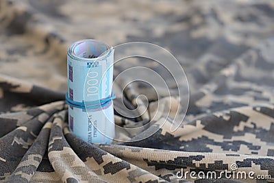 Ukrainian hryvnia bills on fabric with texture of Ukrainian military pixeled camouflage. Cloth with camo pattern in grey Stock Photo