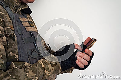 Ukrainian soldier in military pixel unform and bulletproof vest jacket with banner of flag of Ukraine tapping on smartphone Stock Photo