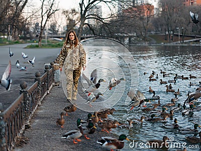 Ukrainian woman soldier walking in park during her vacation near of lake and flying ducks Stock Photo