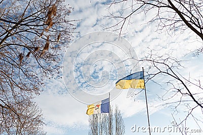 Ukrainian yellow and blue flag and coat of arms of Ukrainian town Izmail flying on blue cloudy sky background Stock Photo