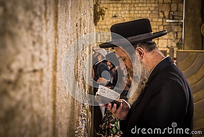 The ultra-orthodox Jewish man (haredi) praying with Tora in hand at Western wall (Wailing Wall) at Jerusalem. Editorial Stock Photo