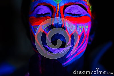 Ultraviolet black light glowing bodyart processing on young woman`s face. Pink and purple dyes in cold blue light Stock Photo