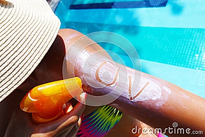 Ultraviolet protection concept with UV text on sunscreen on young woman arm at the swimming pool Stock Photo