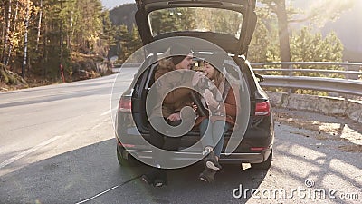 Um casal amoroso em uma viagem O cara e a garota estão sentados no porta-malas aberto do carro, comendo sanduíches Eles video estoque Um casal amoroso em uma viagem O cara e a garota estão sentados no porta-malas aberto do carro, comendo sanduíches Eles video estoque