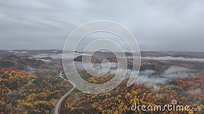 Um drone sobe acima de uma rodovia sinuosa em uma floresta mista de outono perto das montanhas em neblina densa video estoque Um drone sobe acima de uma rodovia sinuosa em uma floresta mista de outono perto das montanhas em neblina densa video estoque