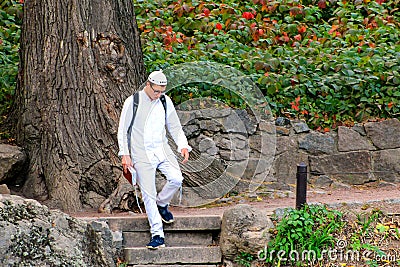 Uman, Ukraine, 22 09 2017. A young Hasid boy in traditional white clothes walking in the park with a prayer book Editorial Stock Photo