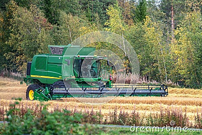 UMEA,SWEDEN - SEPTEMBER 12, 2020: Combine harvester, harvesting at small wheat field, on countryside, Sweden. Wheat field is Editorial Stock Photo