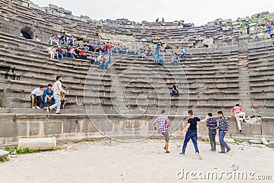 UMM QAIS, JORDAN - MARCH 30, 2017: Young boy tourists visit the West Theatre ruins in Umm Qa Editorial Stock Photo